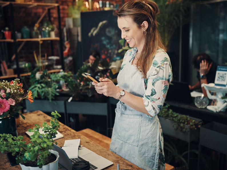 Businesswoman Standing In Her Floristry And Using Her Mobile Phone