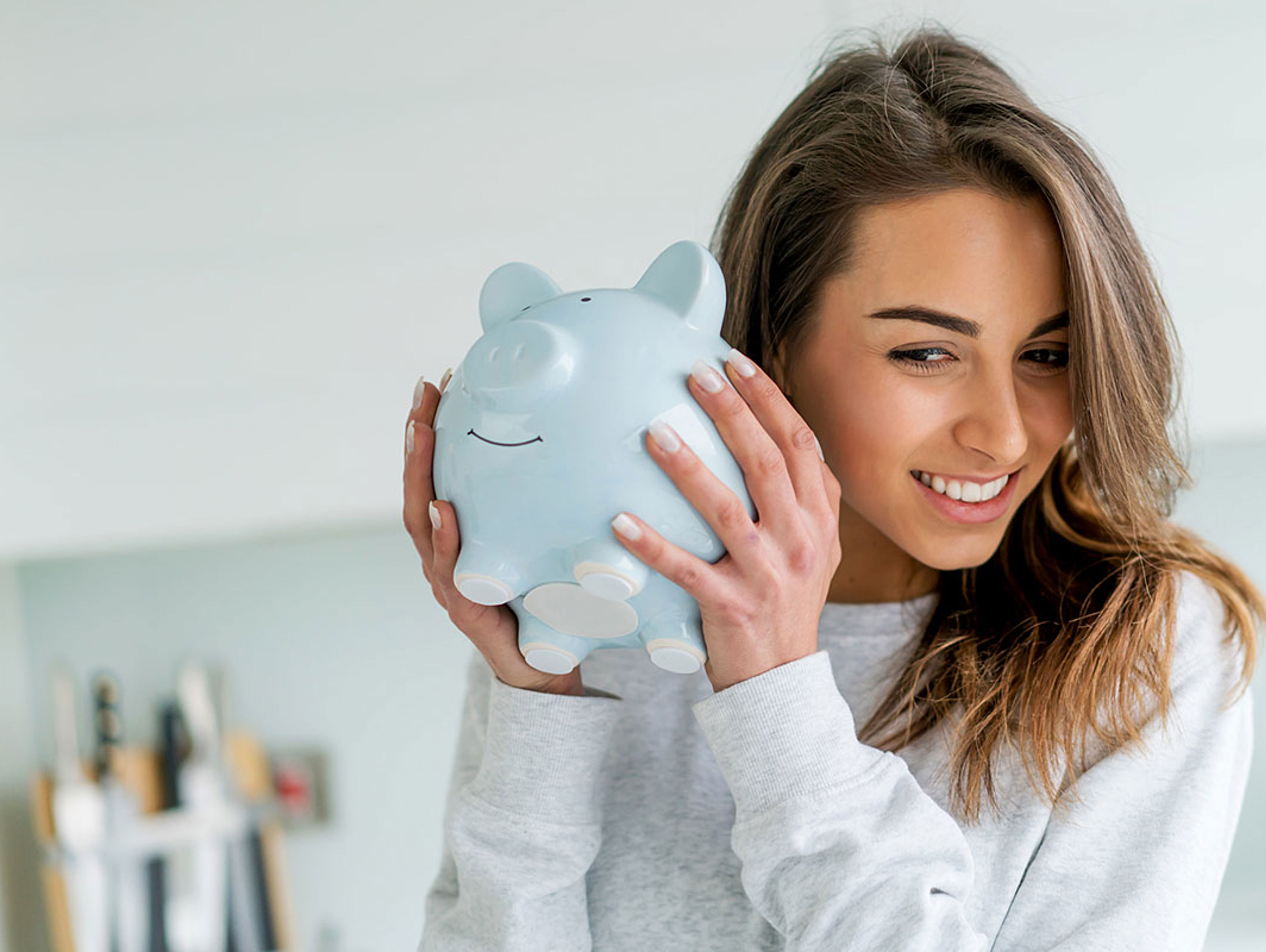 Woman Holding Piggy Bank To Her Ear