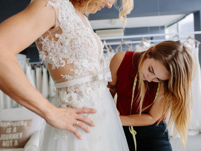 Dress Designer Fitting Wedding Gown To Woman