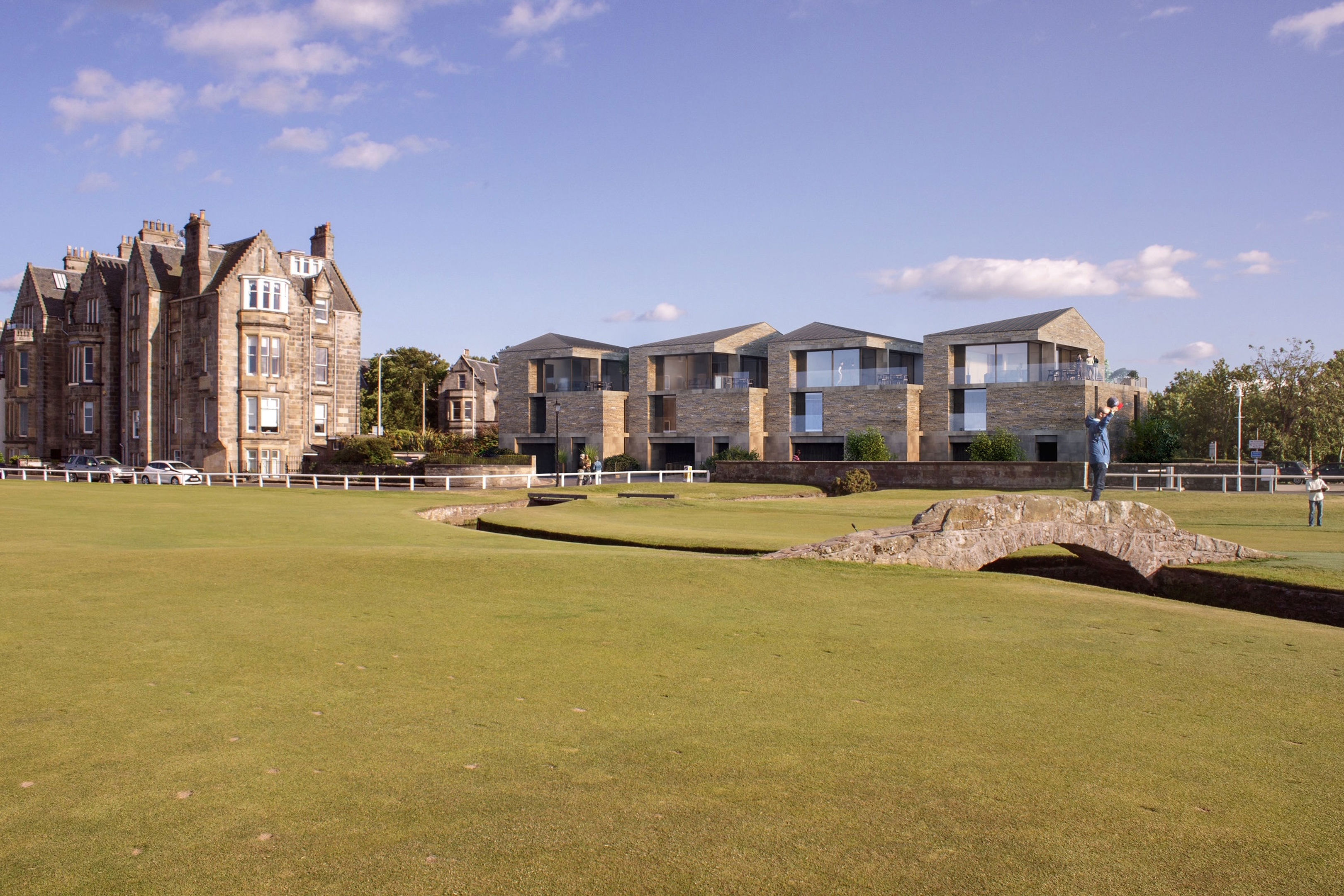 A stone bridge crosses a golf course with modern buildings on the right and a historic stone building on the left, under a blue sky scattered with a few clouds.
