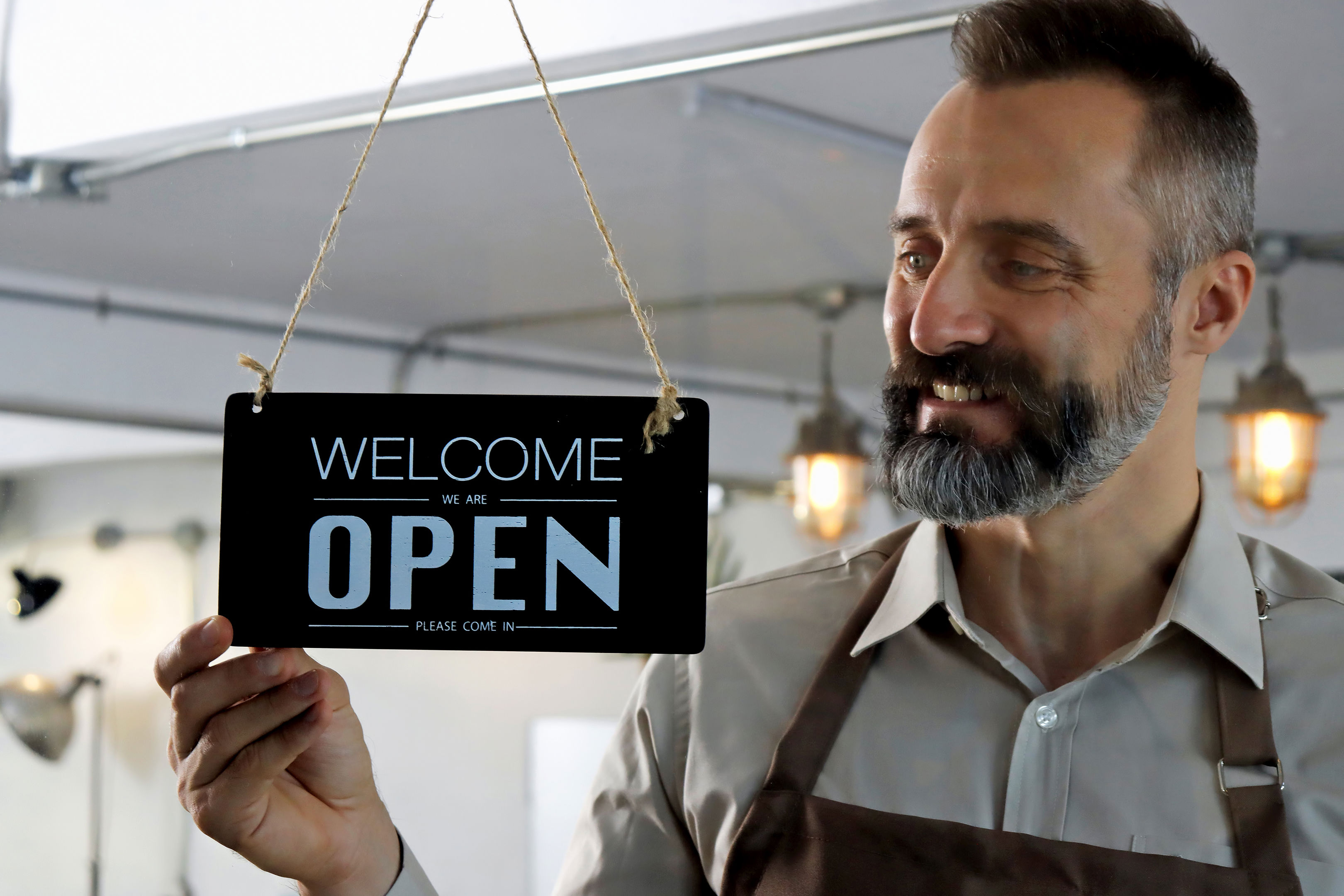 Man In Apron Putting Nameplate On The Entrance Door