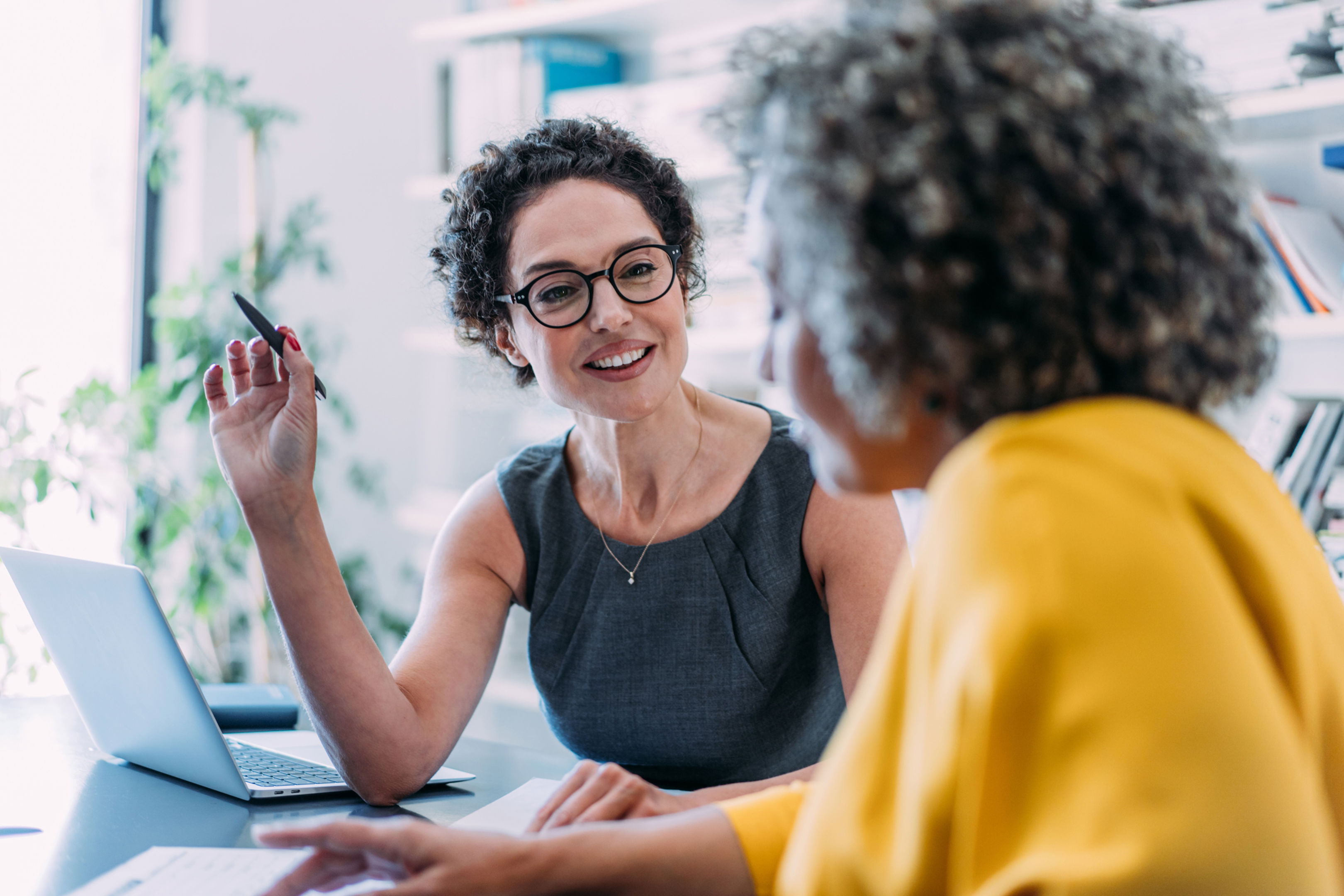 Shot of two businesswomen sharing ideas during a meeting in the office. Businesswomen discussing important documentation in the workplace. Two business people in office working on business reports.
