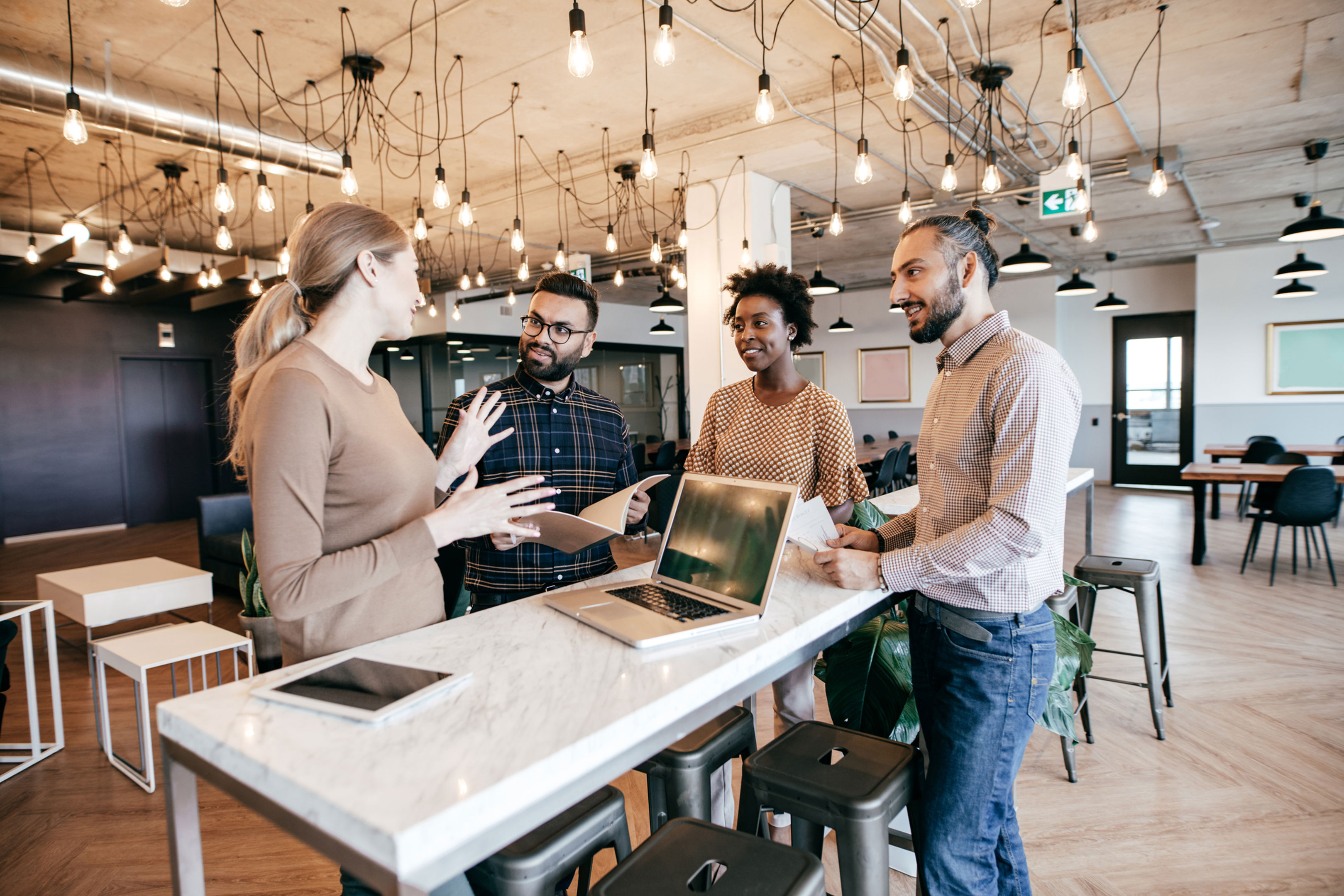 Group of co-workers standing around bench discussing work