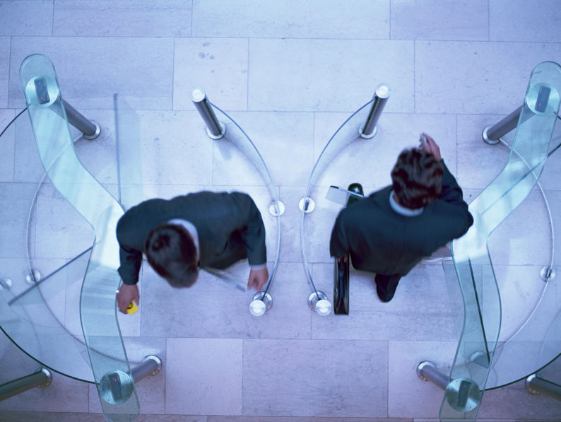 Two businessmen entering and exiting an office