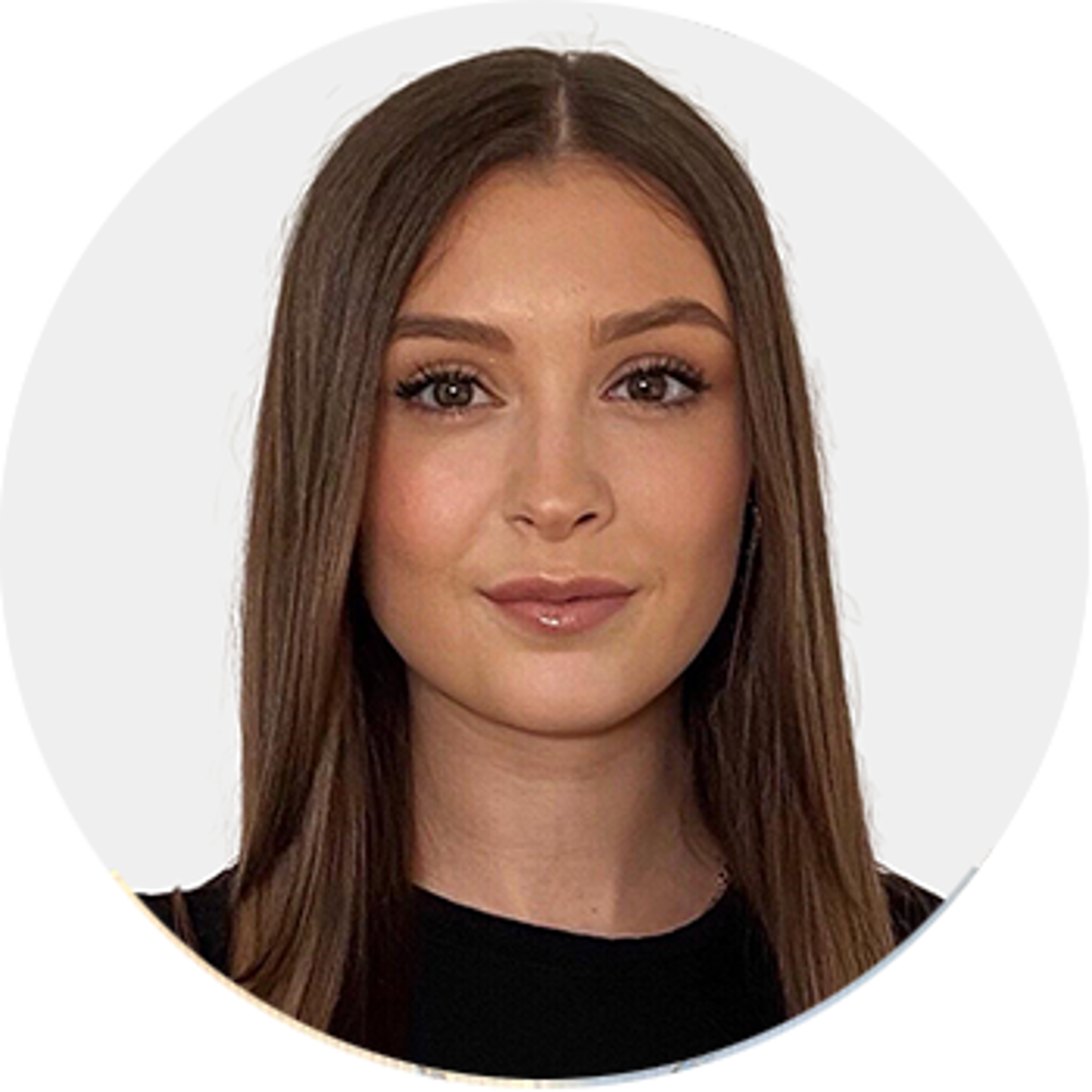 A young woman with long straight brown hair and light makeup, wearing a black top, is posed against a plain white background and looking directly at the camera.