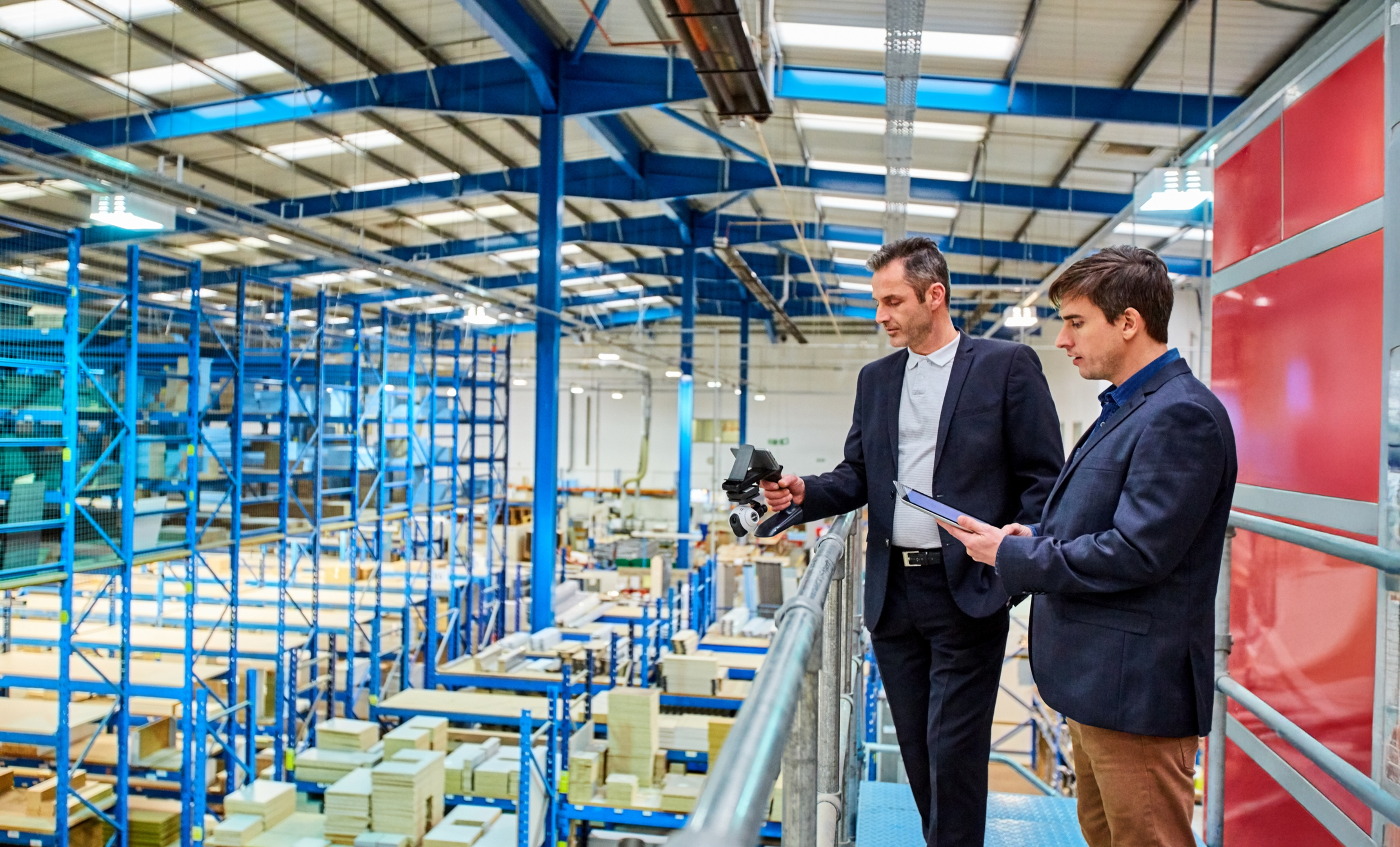 A person wearing safety glasses uses a screwdriver to install or repair a video doorbell on a brick wall next to a door.