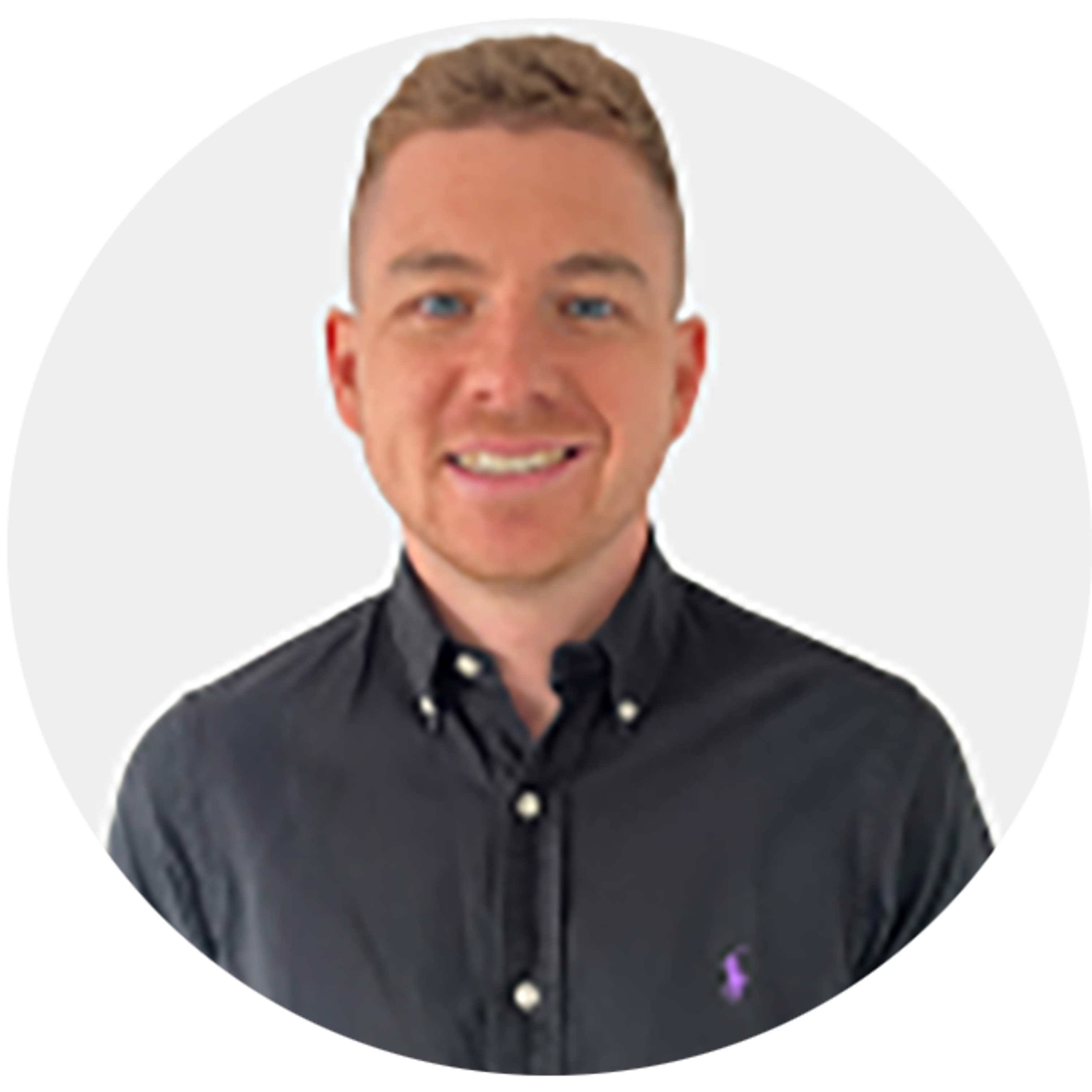 A smiling man with short light brown hair wearing a black button-up shirt stands against a plain white background.