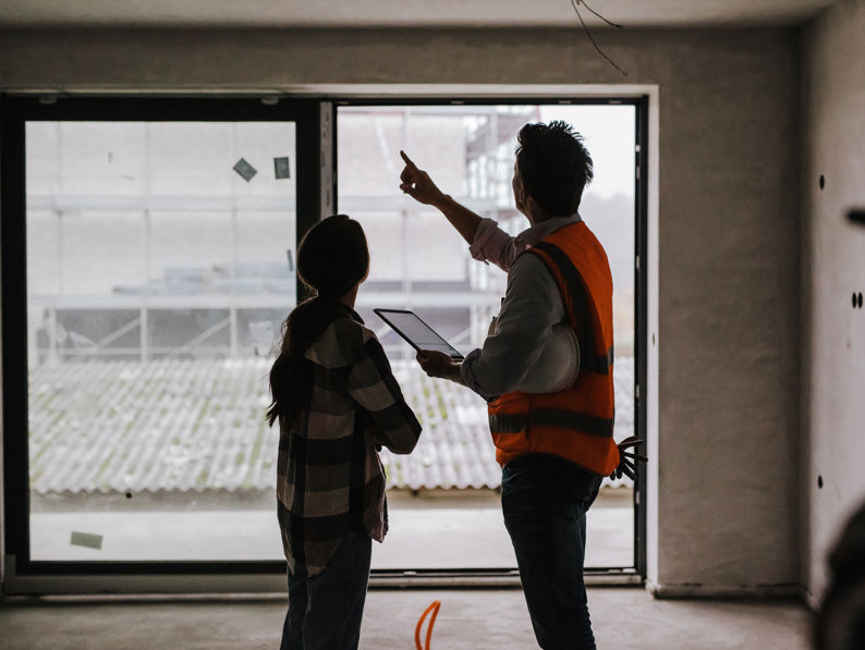 Customer With Architect Evaluating Work Inside An Under Construction Site