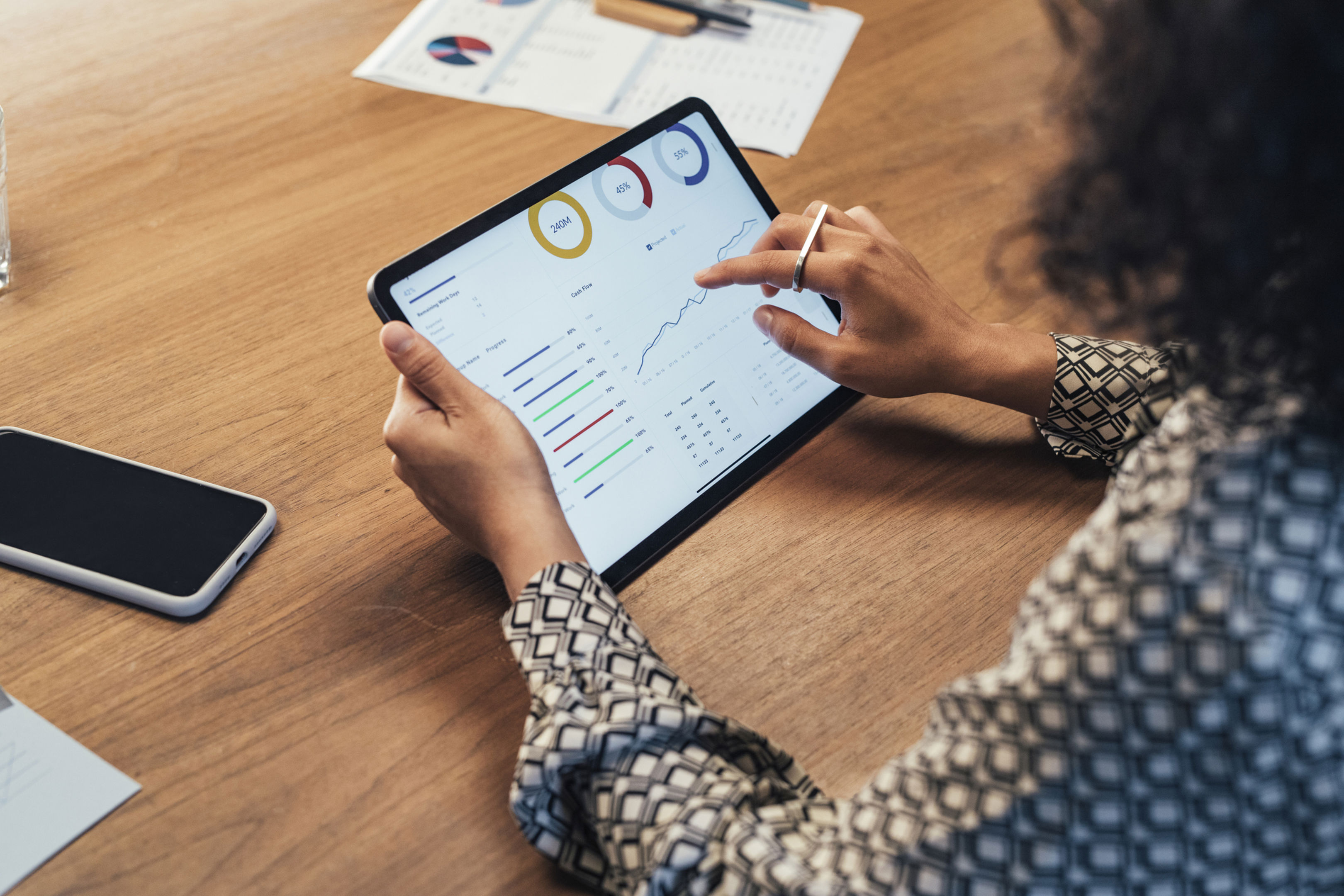 A businesswomen holding a tablet looking at graphs and tables