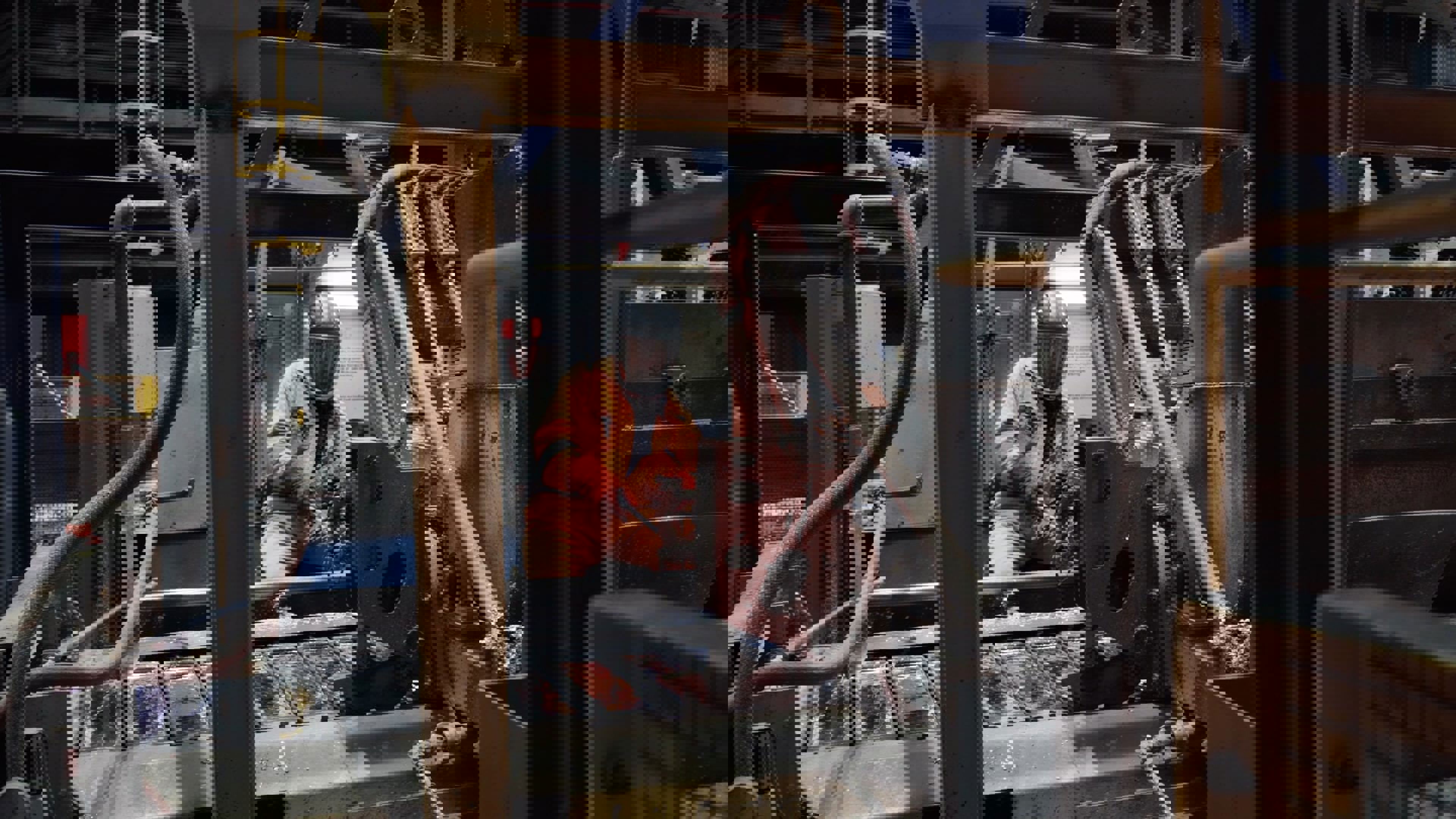 The image appears distorted with digital glitches, making the scene unclear. Horizontal and vertical lines of pixelation obscure the details, and colors such as gray, black, orange, and brown are visible throughout the image.