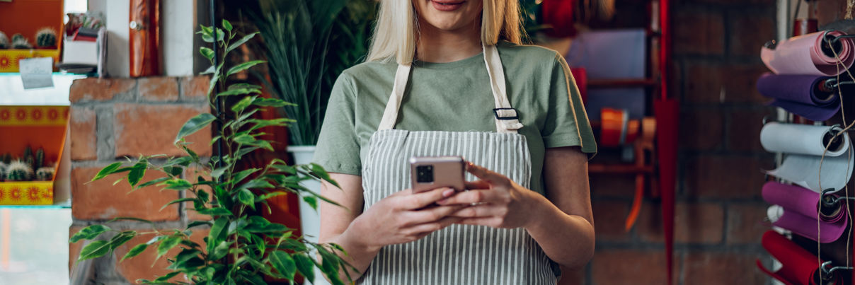 Florist Using A Smartphone While Working In A Flower Shop