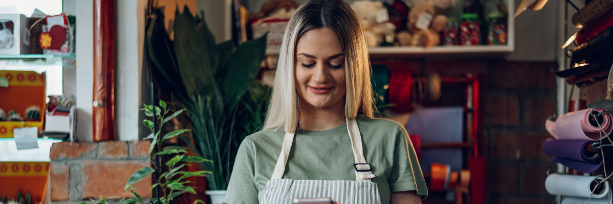 Florist Using A Smartphone While Working In A Flower Shop