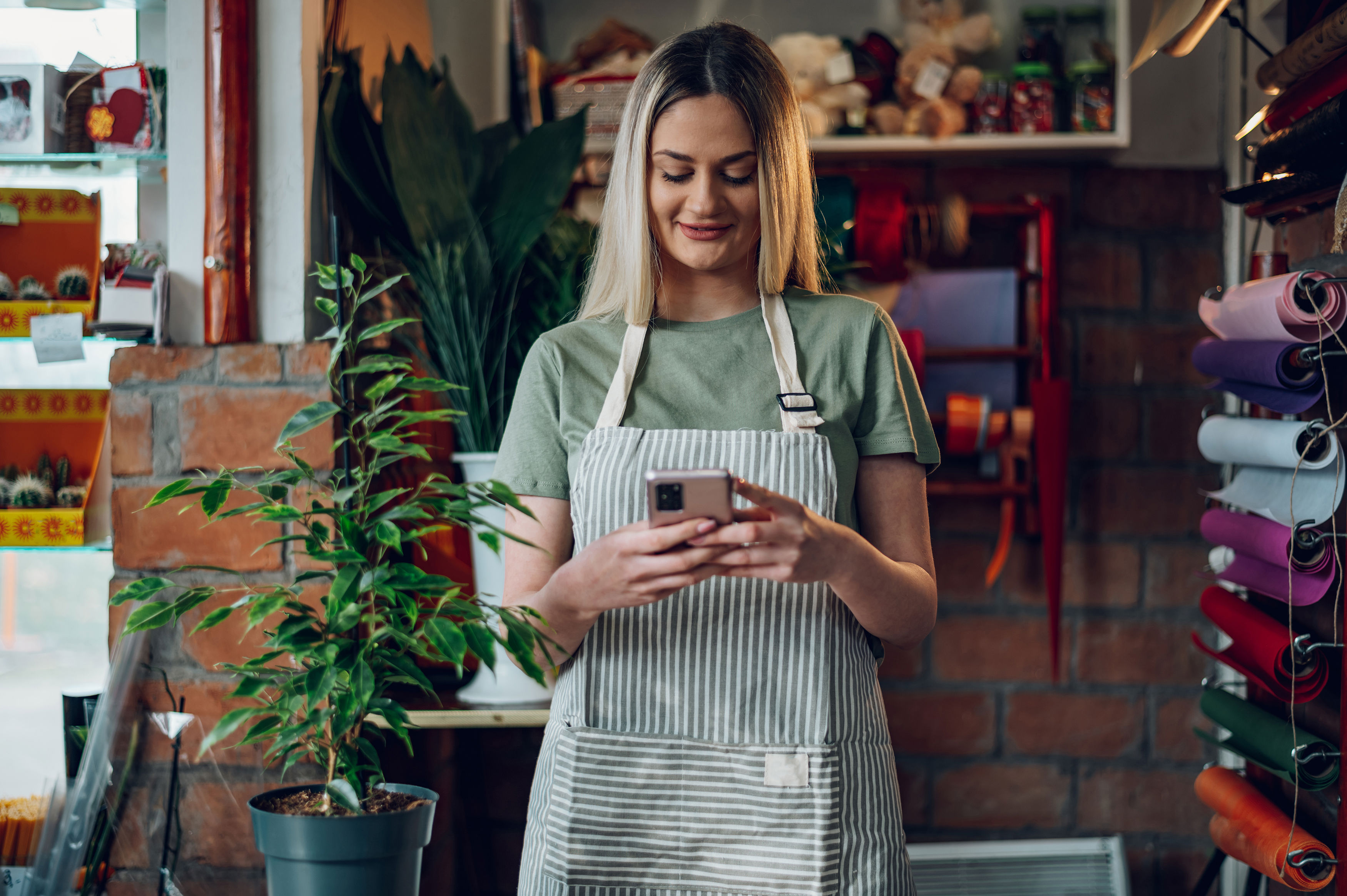 Florist Using A Smartphone While Working In A Flower Shop