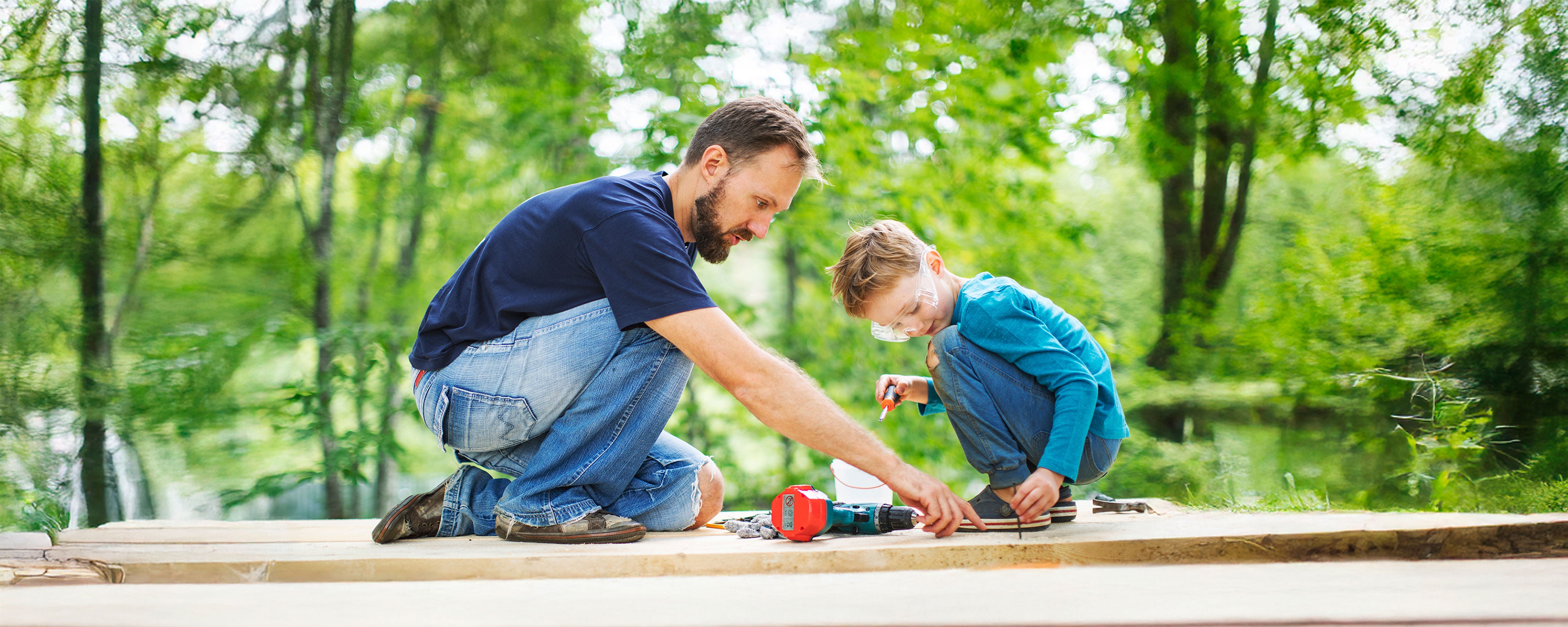 A person in a yellow raincoat stands on a rocky, misty shore looking out at the ocean, with grey clouds above and waves crashing against the rocks.