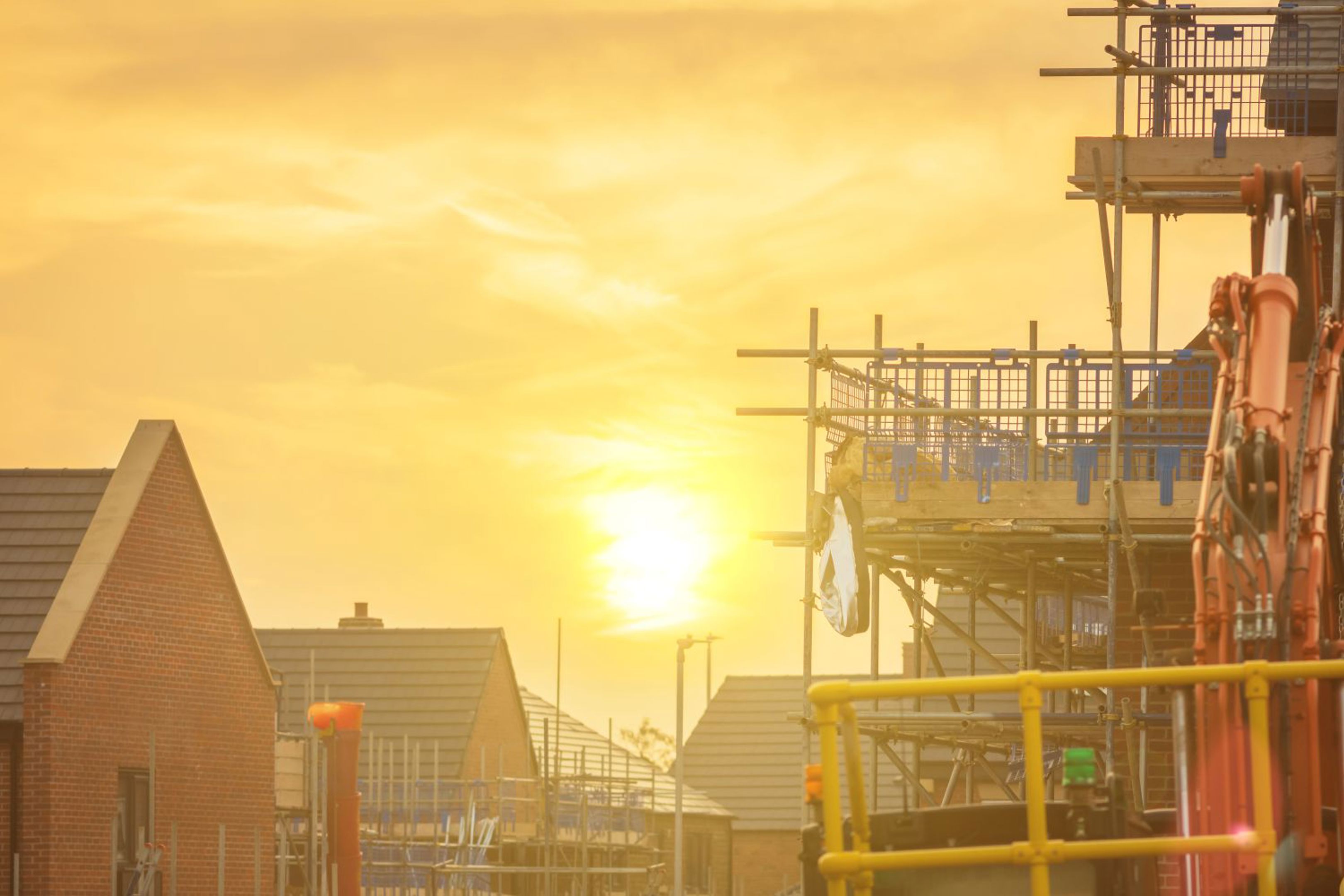 Construction site with scaffolding and building equipment at sunset.