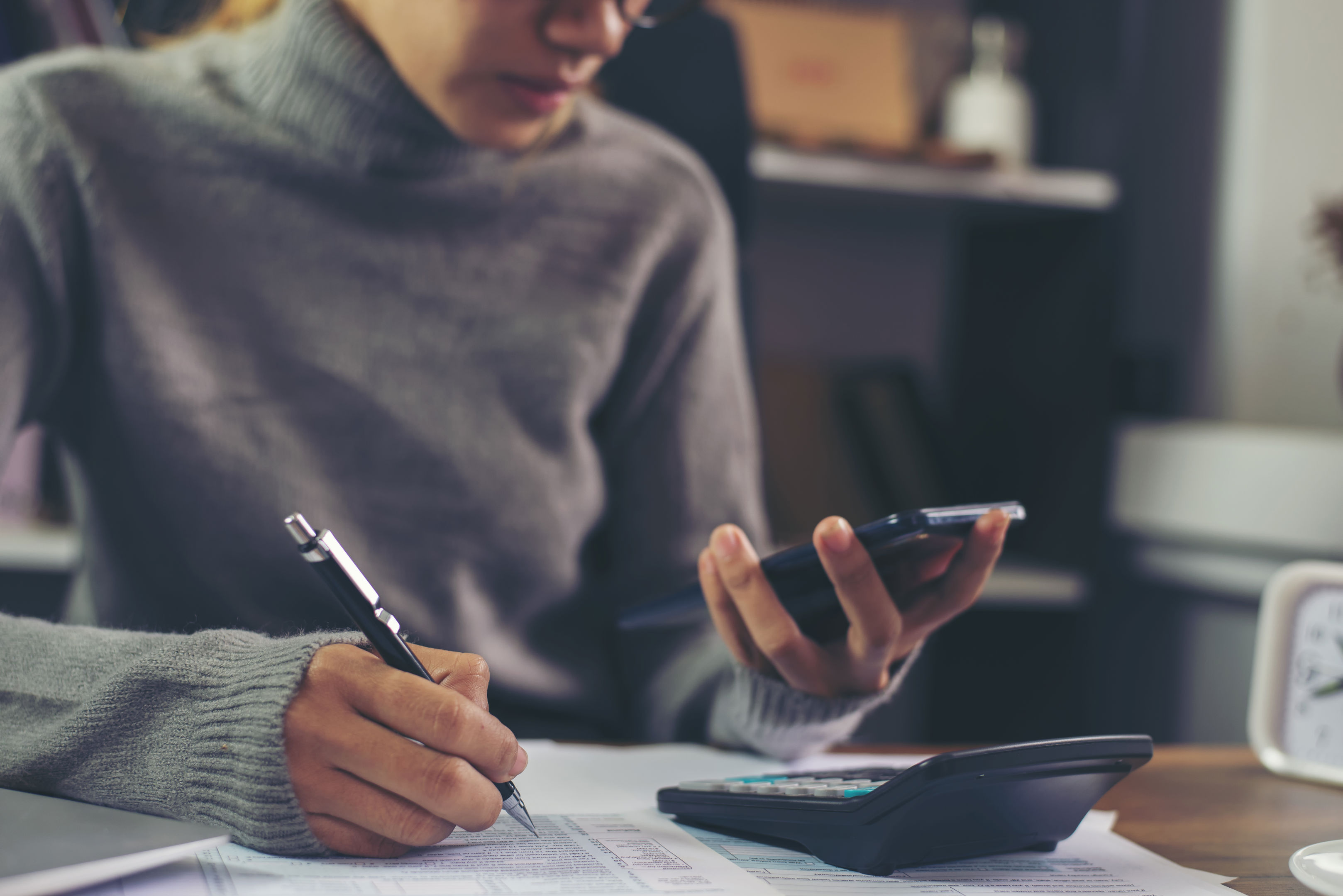 Business woman wear glasses calculating changes to budget and using mobile phone