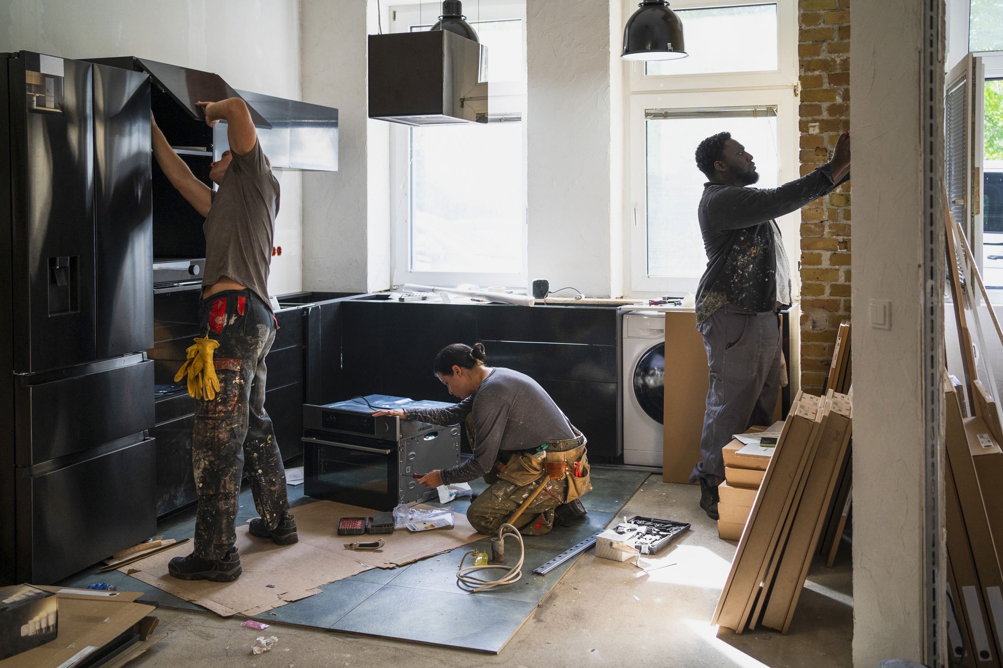 Three Work People Finishing A Kitchen