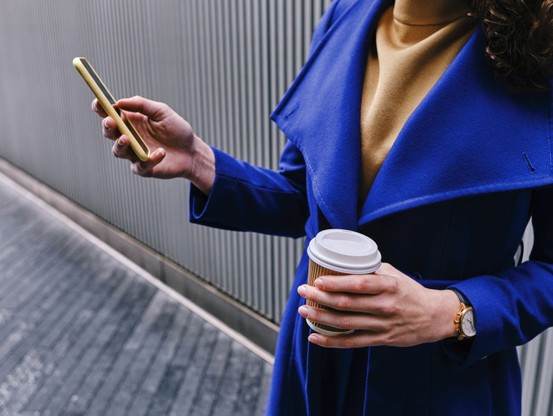 Businesswoman Working On Mobile Phone While Holding Coffee Cup